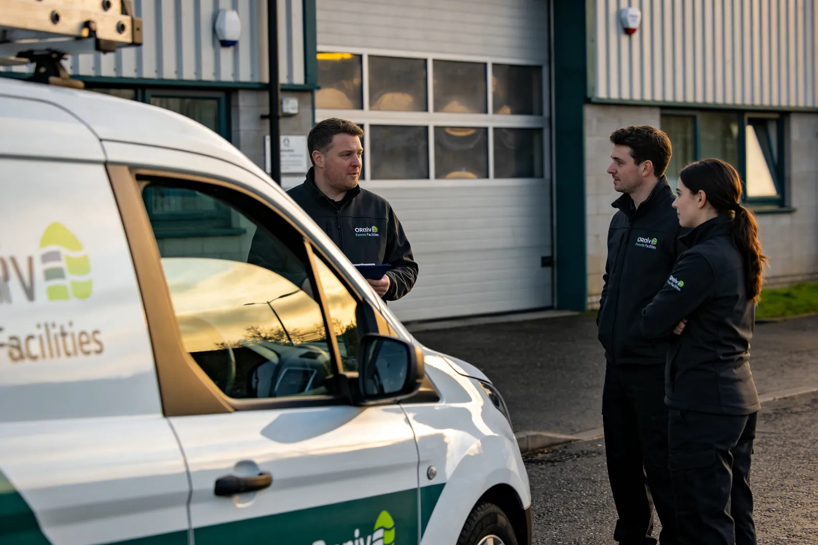 An ORVO facilities team briefing beside a van outside a building